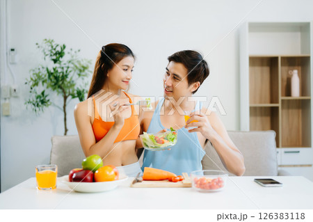 Fitness duo celebrating healthy living with fresh salad, fruits, and juice. A perfect balance of wellness, nutrition 126383118