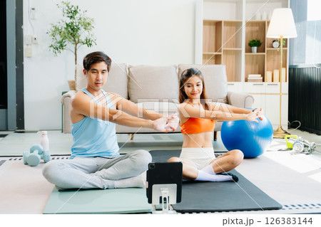 Fitness duo high fiving during an energetic workout session at home, featuring yoga mats, gym equipment 126383144