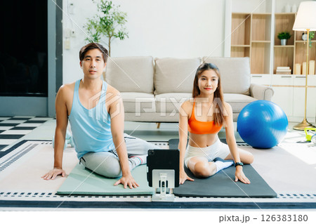 Fitness duo high fiving during an energetic workout session at home, featuring yoga mats, gym equipment 126383180
