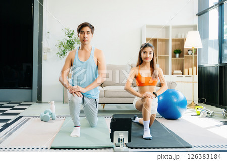 Fitness duo high fiving during an energetic workout session at home, featuring yoga mats, gym equipment 126383184
