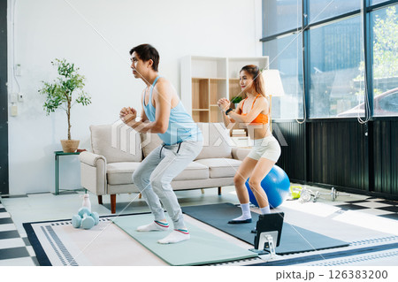 Fitness duo high fiving during an energetic workout session at home, featuring yoga mats, gym equipment Fitness duo high fiving during an energetic workout session at home, featuring yoga mats, gym equipment 126383200