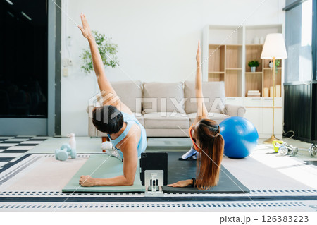 Fitness duo high fiving during an energetic workout session at home, featuring yoga mats, gym equipment Fitness duo high fiving during an energetic workout session at home, featuring yoga mats, gym equipment 126383223