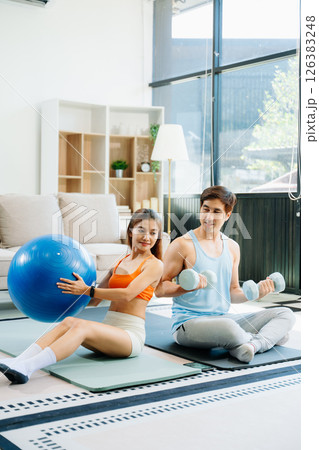 Fitness duo high fiving during an energetic workout session at home, featuring yoga mats, gym equipment Fitness duo high fiving during an energetic workout session at home, featuring yoga mats, gym equipment 126383248