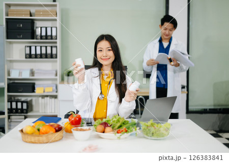 Professional nutritionist reviewing fresh vegetables and supplements for diet planning, health care, 126383841