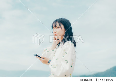穏やかな海を背景にスマートフォンを操作する若い女性 126384509