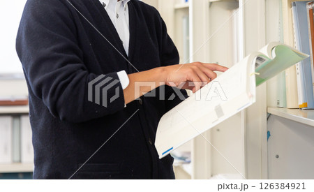 オフィスの書庫で本を広げる男性の手元 資料を指さす手 126384921