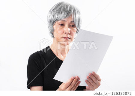 虚ろな目で書類を見つめる白髪のシニア女性 虚ろな目で書類を見つめる白髪のシニア女性 126385873