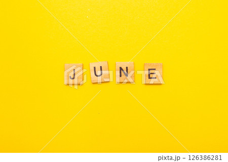 Top view of word June month made by wooden cubes with letters on a yellow bright background 126386281