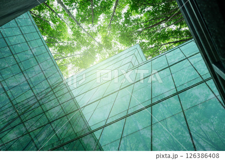 Eco-friendly building in modern city. Sustainable glass office building with trees for reducing carbon dioxide. Office building with green environment. Corporate building reduce CO2. Net zero emission 126386408
