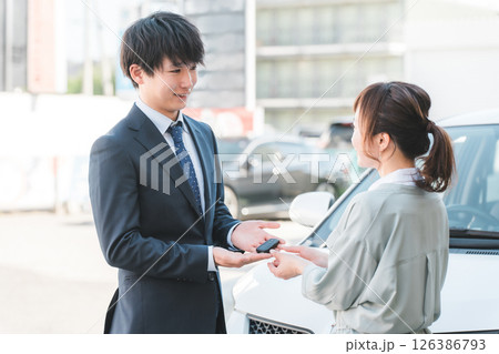 女性客に車の鍵を渡す若いセールスマン,営業マンの男性 126386793