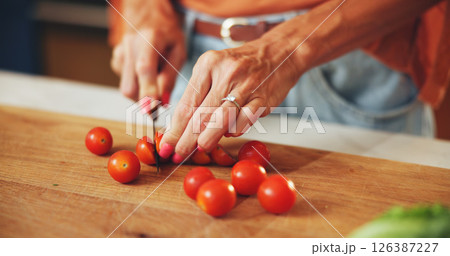 Cooking, woman and hands cut tomatoes in kitchen for dinner salad, organic recipe and vegetarian food. Wood board, person and vegetable ingredients for meal preparation, lunch cuisine and nutrition 126387227