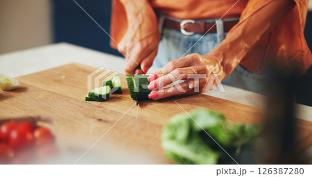Cooking, woman and hands cut vegetables in kitchen for healthy salad, organic recipe and nutrition. Closeup, person and cucumber ingredients for meal preparation, lunch cuisine and vegan food in home 126387280