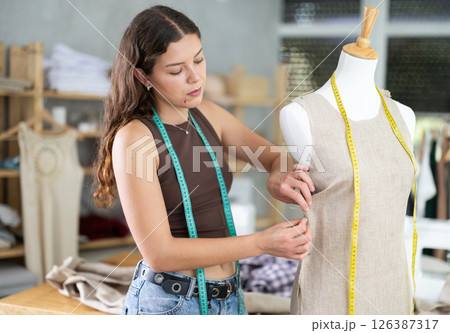Fashion designer fitting dress on mannequin in dressmaker studio 126387317