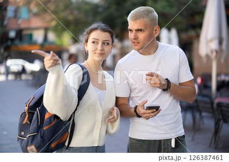 Lost guy and girl are looking at phone navigator app Lost guy and girl are looking at phone navigator app 126387461