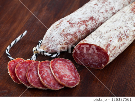 Spanish longaniza salami sausages cut in slices on a woodefn desk Spanish longaniza salami sausages cut in slices on a woodefn desk 126387561