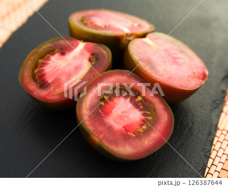 Black halves of tomatoes on black stone board Black halves of tomatoes on black stone board 126387644