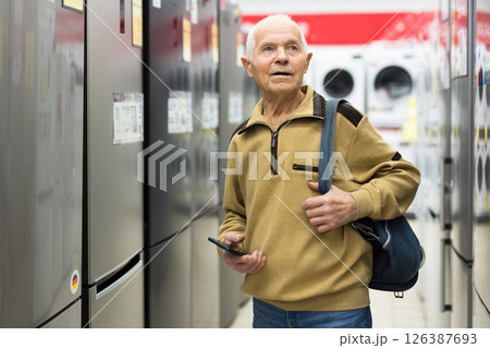 Elderly man choosing refrigerator in showroom of electrical appliance store Elderly man choosing refrigerator in showroom of electrical appliance store 126387693