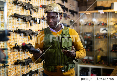 African american man in army uniform with weapon in military shop 126387700