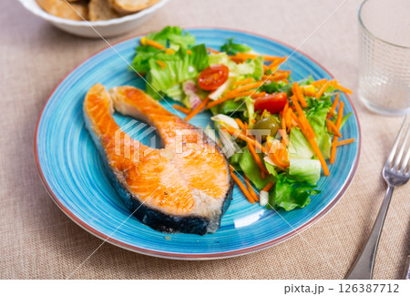 Baked salmon served with salad and vegetables 126387712