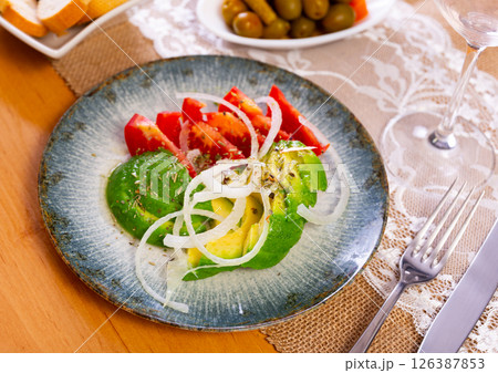 Vegetable appetizer of sliced tomatoes, avocado and onion 126387853