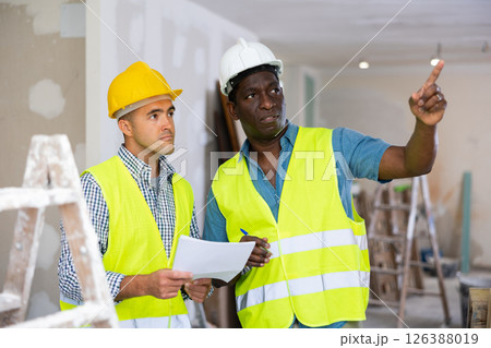 Man and man builders discussing project documentation 126388019