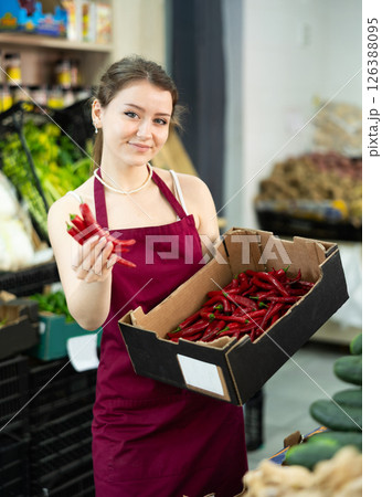 Young woman seller with box of peppers Young woman seller with box of peppers 126388095