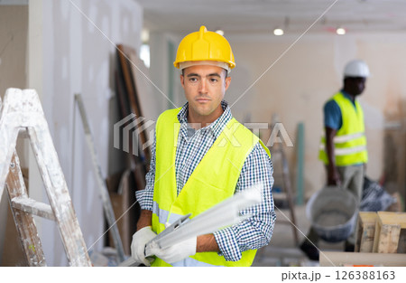 Builder carrying construction detail while working in apartment Builder carrying construction detail while working in apartment 126388163