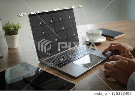2025 calendar person using laptop with digital calendar overlay screen workspace with smartphone notebook coffee cup and plant modern office 126388497