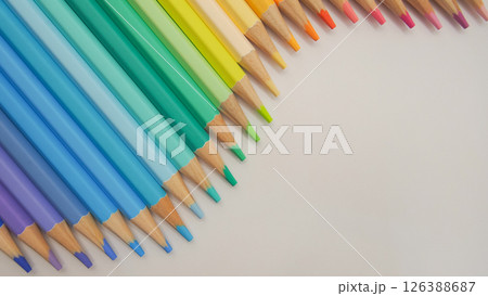 a clean arrangement of sharpened colored pencils transitioning from cool blues and purples through greens to warm oranges and pinks, against a soft neutral background. a clean arrangement of sharpened colored pencils transitioning from cool blues and purples through greens to warm oranges and pinks, against a soft neutral background. 126388687
