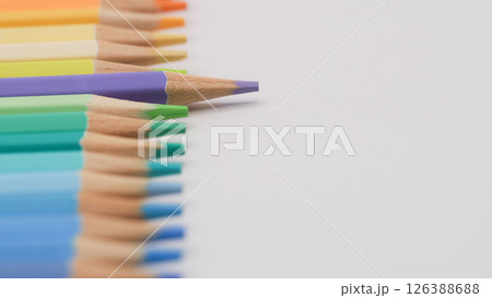 a neat row of colored pencils arranged by hue, with one vivid purple pencil breaking the uniformity by pointing sideways, drawing immediate focus a neat row of colored pencils arranged by hue, with one vivid purple pencil breaking the uniformity by pointing sideways, drawing immediate focus 126388688