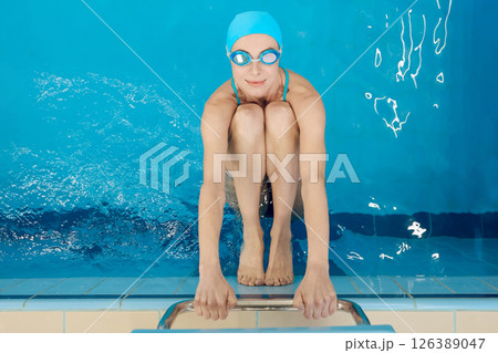 Woman in blue swimming cap enjoying aqua fitness in the swimming pool Woman in blue swimming cap enjoying aqua fitness in the swimming pool 126389047