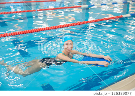 Young woman swimming with a board and looking contented Young woman swimming with a board and looking contented 126389077