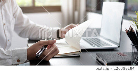 Closeup businessman writing on notebook on table with laptop. 126389194