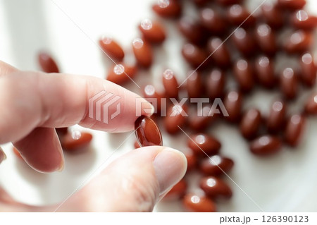 プラセンタサプリメントを一粒つまんでいる50歳代女性の指 126390123
