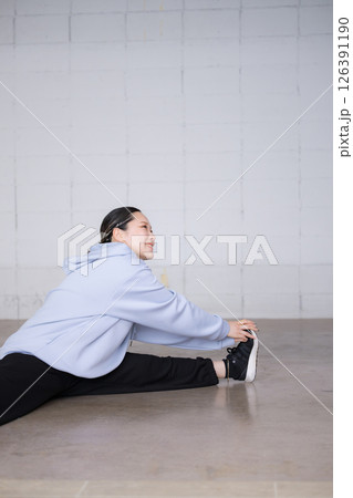 ダンスのやスポーツの準備運動をする女性　ストレッチで腕や足をのばす　開脚で前屈 126391190