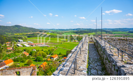 Visitors enjoy a panoramic view from the Donjon Tower of Rabi Castle in Czechia. The lush green landscape stretches across the horizon, showcasing rolling hills and quaint villages below. Visitors enjoy a panoramic view from the Donjon Tower of Rabi Castle in Czechia. The lush green landscape stretches across the horizon, showcasing rolling hills and quaint villages below. 126391895