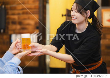 飲食店でビールを運ぶホールスタッフ 126392002