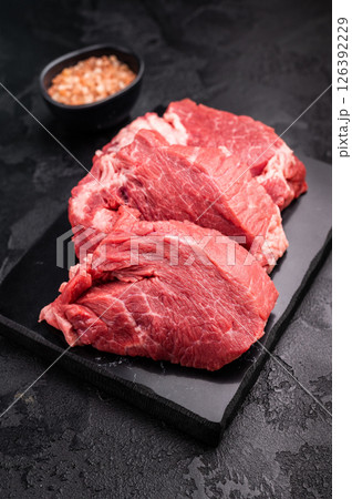 Raw beef boneless shank shin presented with herbs and spices, inspiring bold flavors and unique recipes for adventurous home cooks. black background. top view 126392229