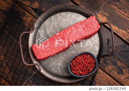 High quality marbled wagyu beef steak, ready to be transformed into a gourmet masterpiece. A delicious choice for any meat lover's palate. wooden background. top view High quality marbled wagyu beef steak, ready to be transformed into a gourmet masterpiece. A delicious choice for any meat lover's palate. wooden background. top view 126392248