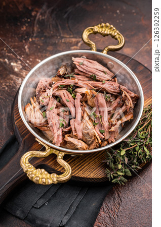 Close-up of succulent pulled brisket piled high on a rustic wooden board, garnished with fresh herbs, delicious meal. brown background. top view Close-up of succulent pulled brisket piled high on a rustic wooden board, garnished with fresh herbs, delicious meal. brown background. top view 126392259