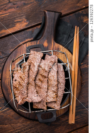 Flavorful yakiniku with juicy wagyu beef slices cooked right at the table. wooden background. top view Flavorful yakiniku with juicy wagyu beef slices cooked right at the table. wooden background. top view 126392278