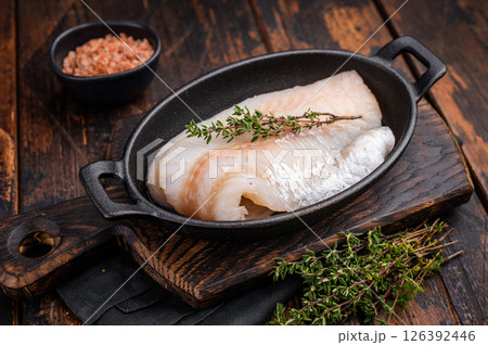Pristine raw cod fillet, waiting to be marinated and cooked to perfection for a delightful dining experience. wooden background. top view Pristine raw cod fillet, waiting to be marinated and cooked to perfection for a delightful dining experience. wooden background. top view 126392446