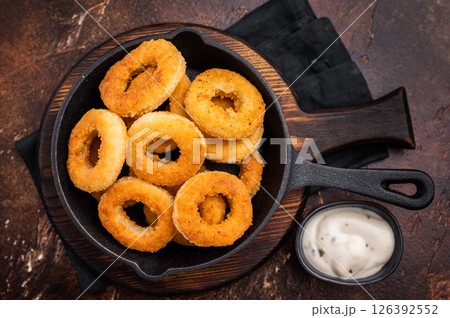 Crispy Fried onion rings, delicious snack in a pan. brown background. top view Crispy Fried onion rings, delicious snack in a pan. brown background. top view 126392552