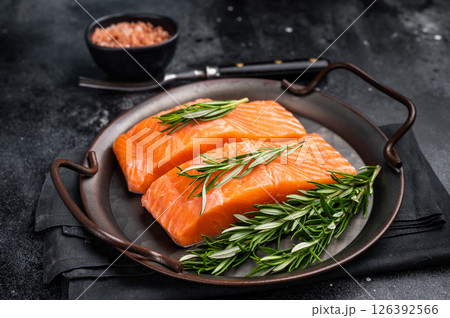 Raw Salmon fillet steak with rosemary ready for cooking. black background. top view Raw Salmon fillet steak with rosemary ready for cooking. black background. top view 126392566