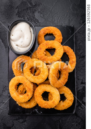 Deep fried squid rings with breading, calamari fastfood snack. black background. top view 126392568