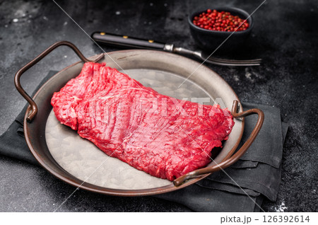 Uncooked flank steak, raw beef flap meat steak. black background. top view Uncooked flank steak, raw beef flap meat steak. black background. top view 126392614