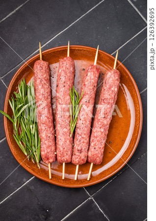 Raw Cevapcici skewers, Cevapi sausages from mince beef and pork meat. black background. top view Raw Cevapcici skewers, Cevapi sausages from mince beef and pork meat. black background. top view 126392695