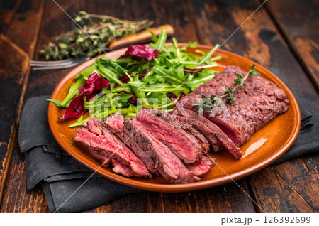 Grilled Skirt machete beef steak, roasted sliced meat on plate with salad. wooden background. top view Grilled Skirt machete beef steak, roasted sliced meat on plate with salad. wooden background. top view 126392699