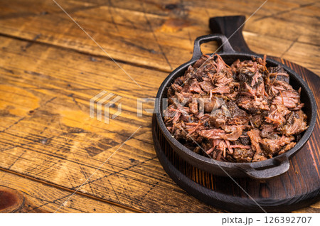 Barbecue wagyu meat torn to bits pulled beef in a skillet. wooden background. top view Barbecue wagyu meat torn to bits pulled beef in a skillet. wooden background. top view 126392707