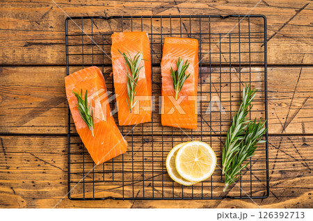 Salmon steaks, raw fish fillets on a rack with rpsemary. wooden background. top view 126392713